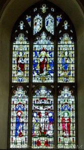 large chancel stained glass window showing jesus on the cross and saints surrounded by angels