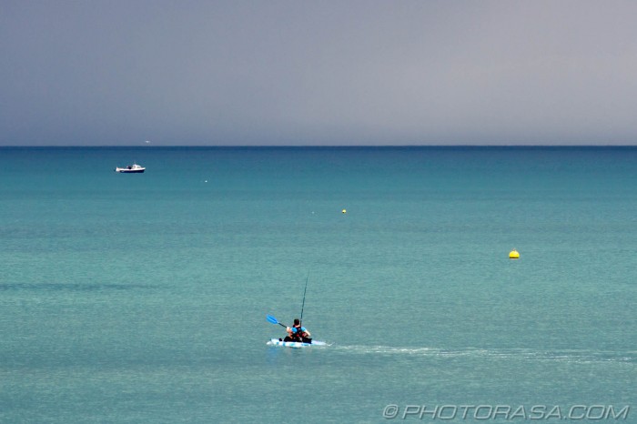 canoeist paddling out to dark blue sea
