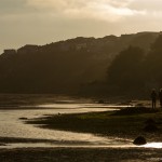 couple walking along estuary at sunset and low tide