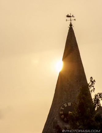 sun peeking from behind loose church spire